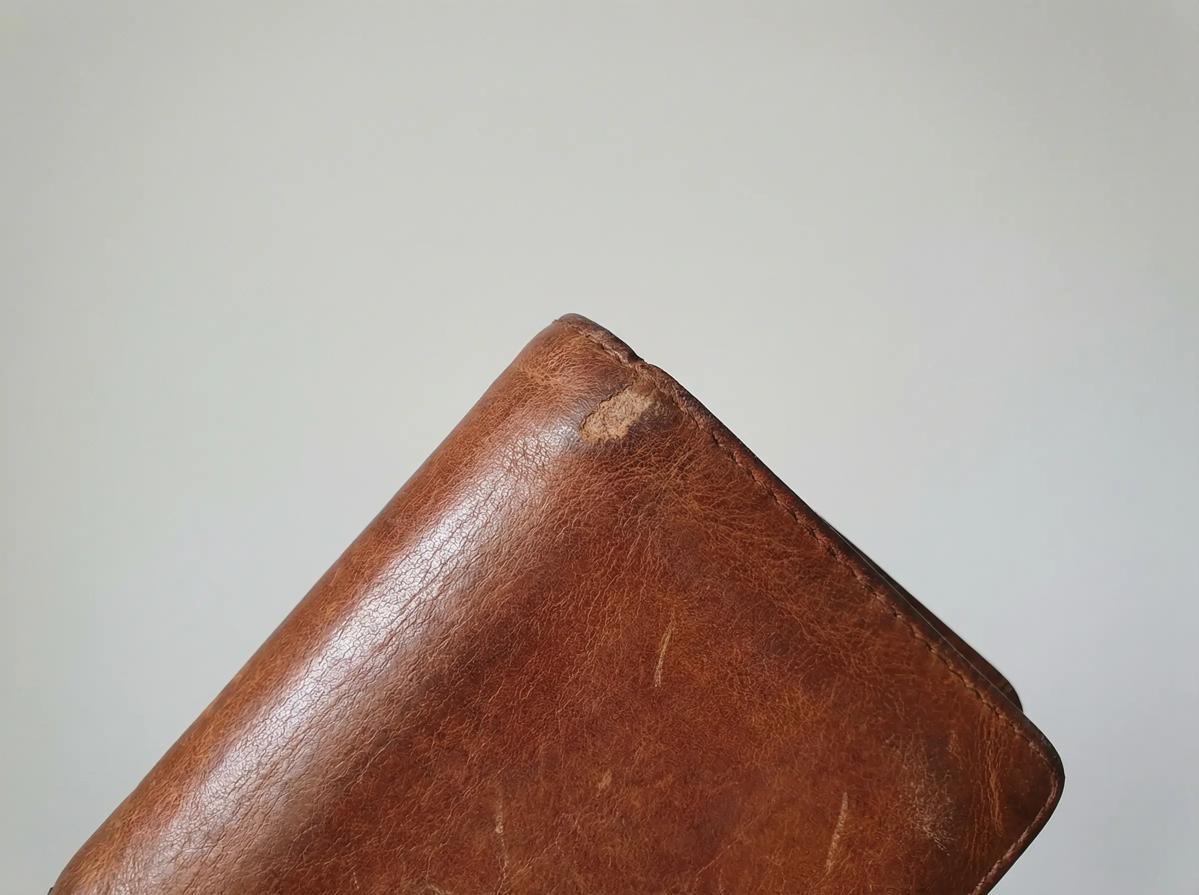 Close-up photograph showing minor wear on wallet corner with clear lighting for honest condition disclosure
